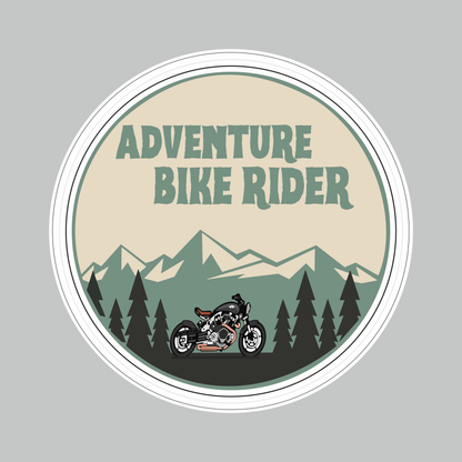 Round Adventure Bike Rider Sticker featuring motorcycle, mountain and pine forest artwork in beige, green and black