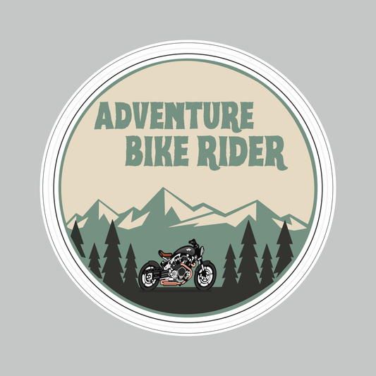 Round Adventure Bike Rider Sticker featuring motorcycle, mountain and pine forest artwork in beige, green and black