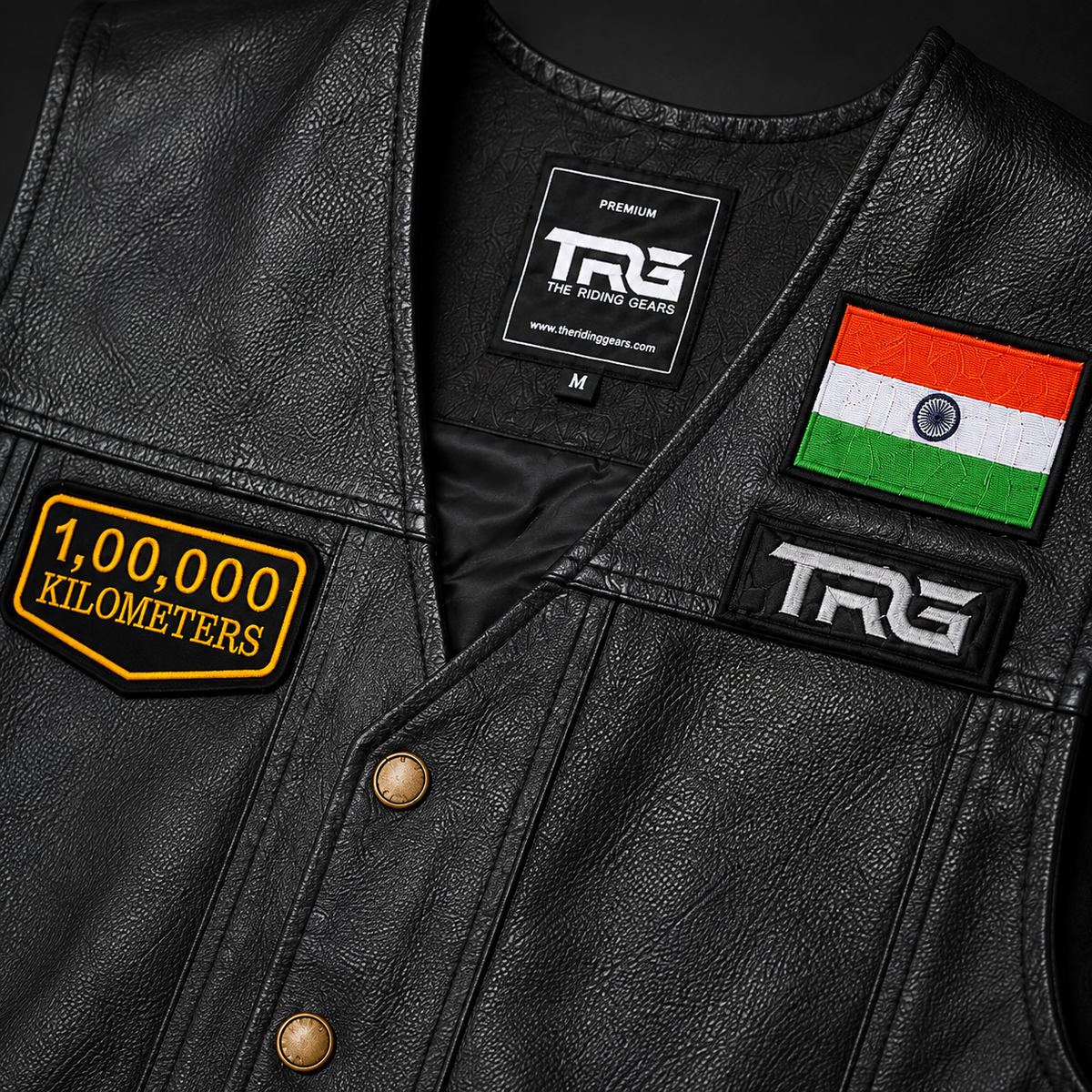 Close-up of 1 Lakh Kilometres embroidered patch on black leather vest showing yellow embroidery, black base and precision stitched border