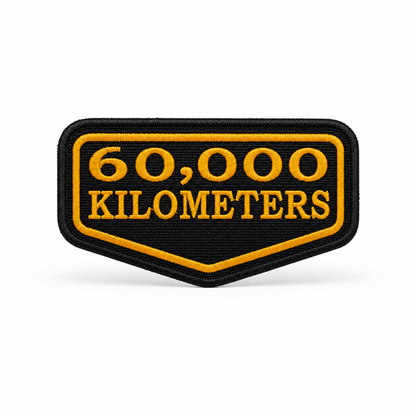 60,000 Kilometres embroidered patch in black and yellow with premium stitched border on white background