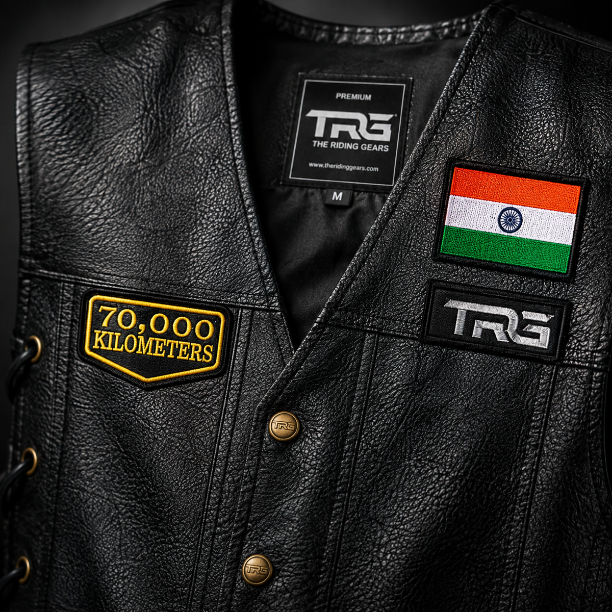 Close-up of 70 Thousand Kilometres embroidered patch on black leather vest showing detailed yellow stitching