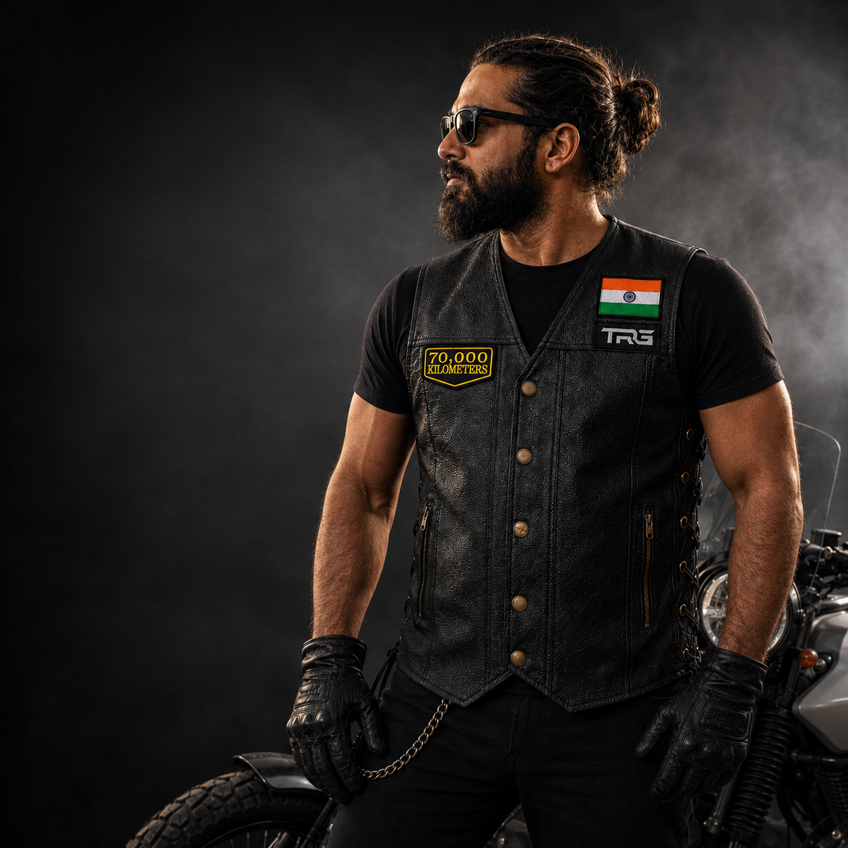 Motorcycle rider wearing 70 Thousand Kilometres embroidered patch on black leather riding vest beside motorcycle