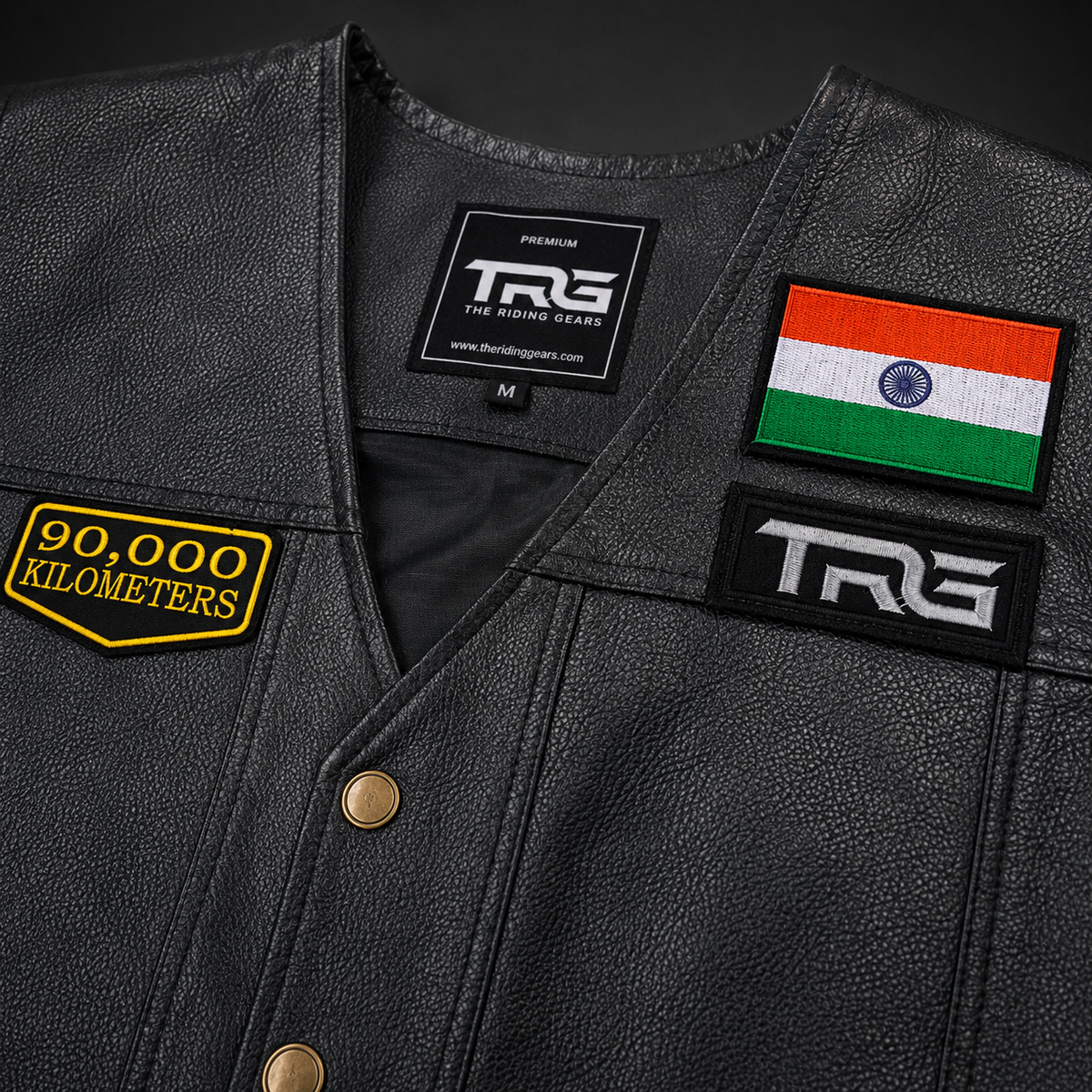 Close-up of 90,000 Kilometres embroidered patch attached to black leather biker vest with Indian flag and TRG patch
