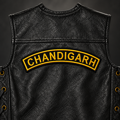 Close-up view of the Chandigarh Top Curved embroidery patch stitched on the upper back of a black leather vest.