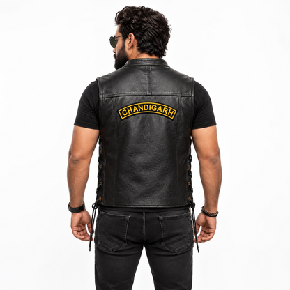 Rear studio view of a man wearing a black leather vest with the Chandigarh Top Curved embroidery patch positioned on the upper back.