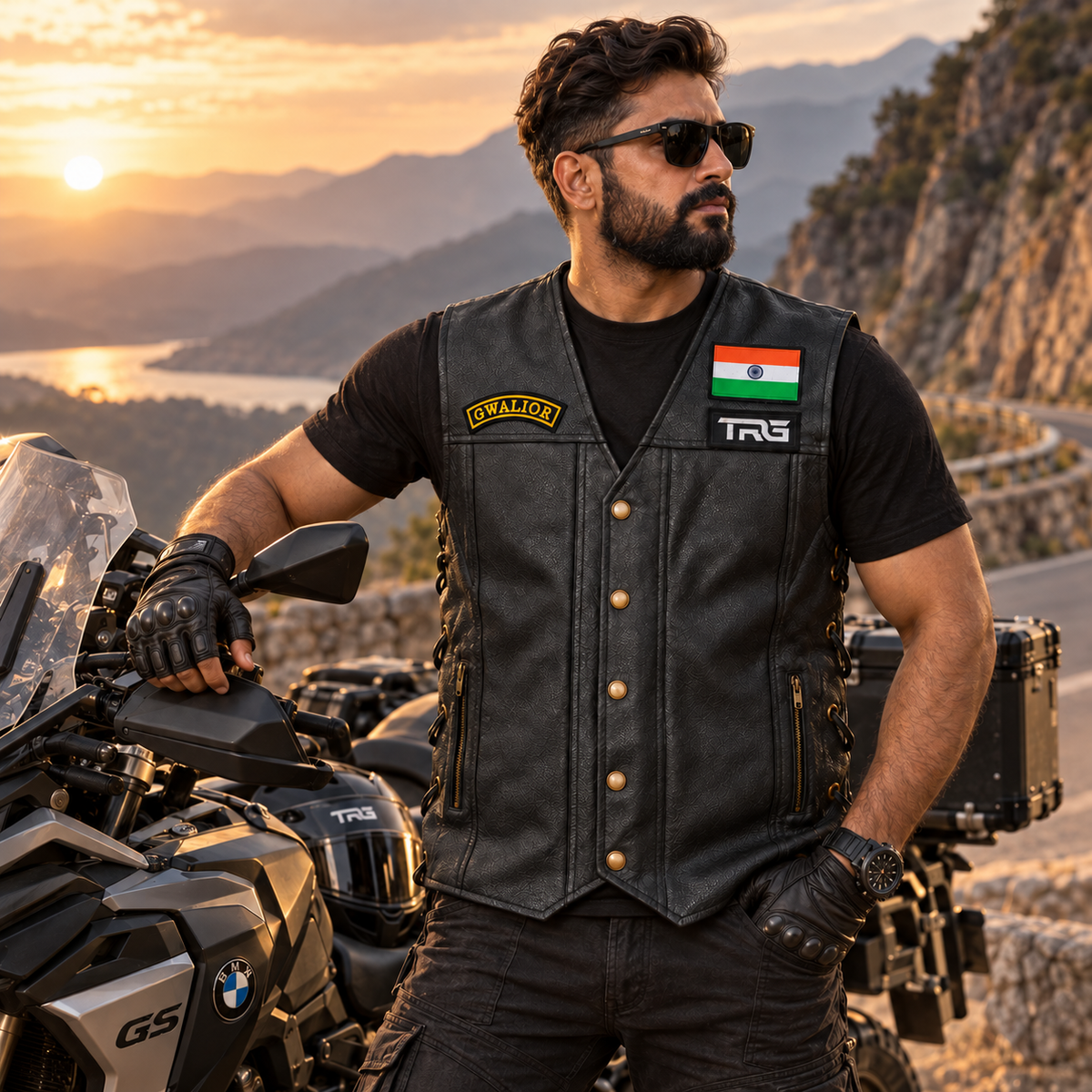 Biker wearing Gwalior embroidered chest patch on a black leather vest beside a motorcycle outdoors.